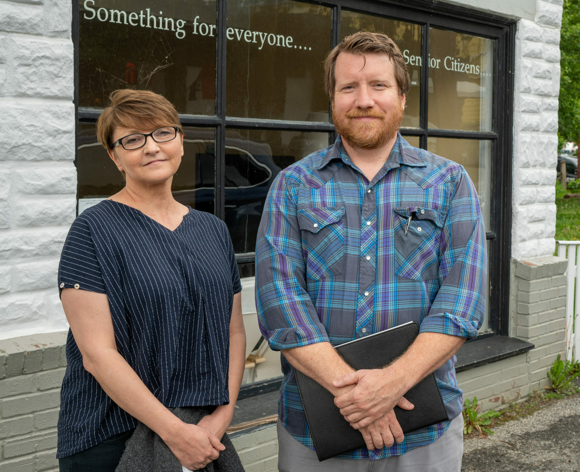 Two staff of NECC stand outside the organization's building.