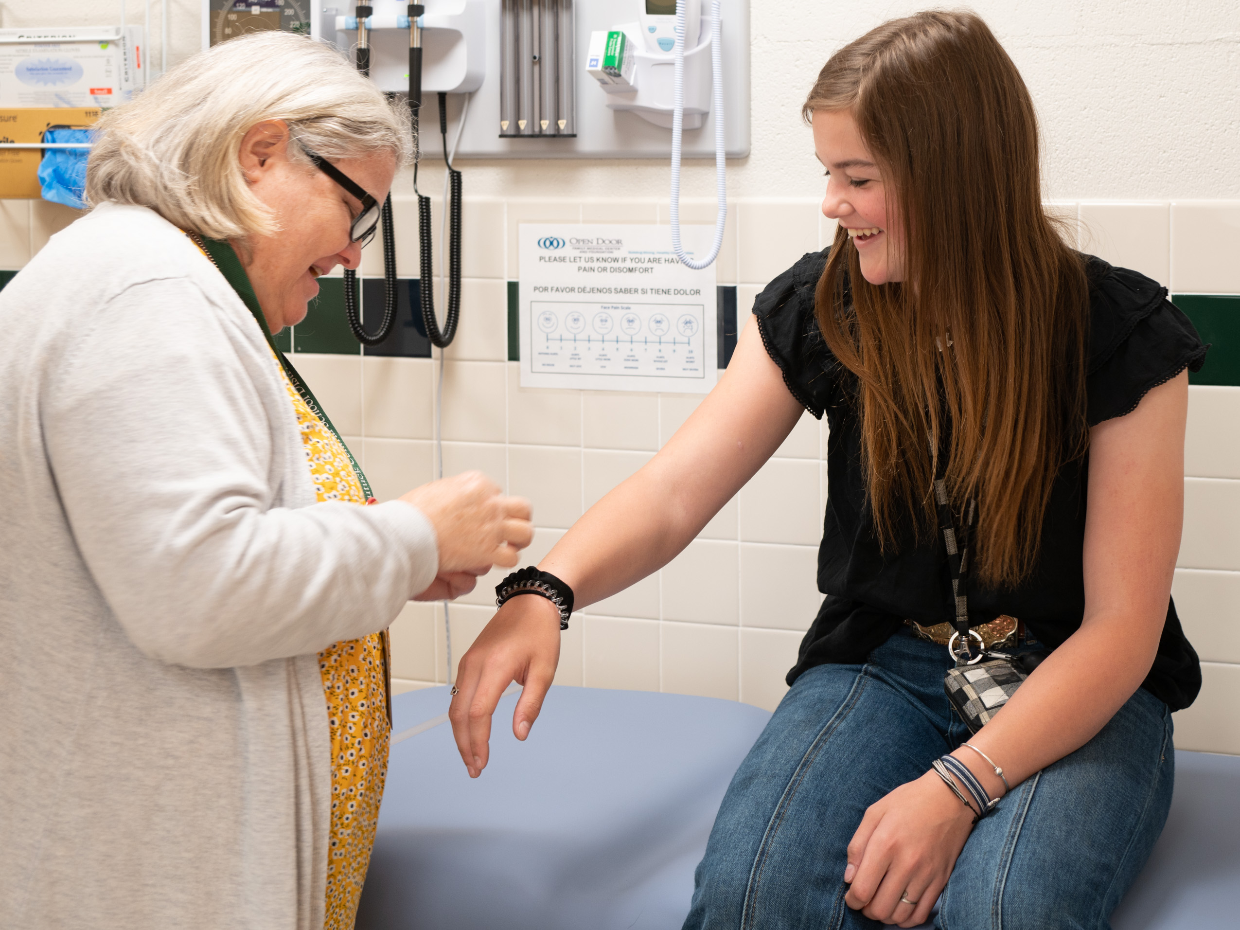 Nurse provides care to teenager in exam room.